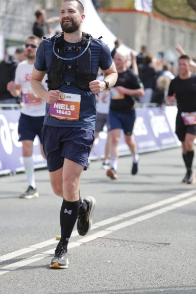 Man in sportkleding loopt een marathon, omringd door andere hardlopers.